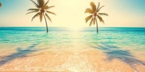 Couple relaxing on a sun lounger by a turquoise sea.