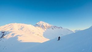 Snowy mountain peak with ski slope and skier.