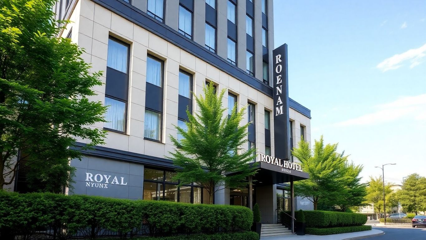 Exterior of the Royal Hotel Bronx with trees and bushes.