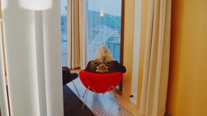a woman sitting in a red chair looking out a window