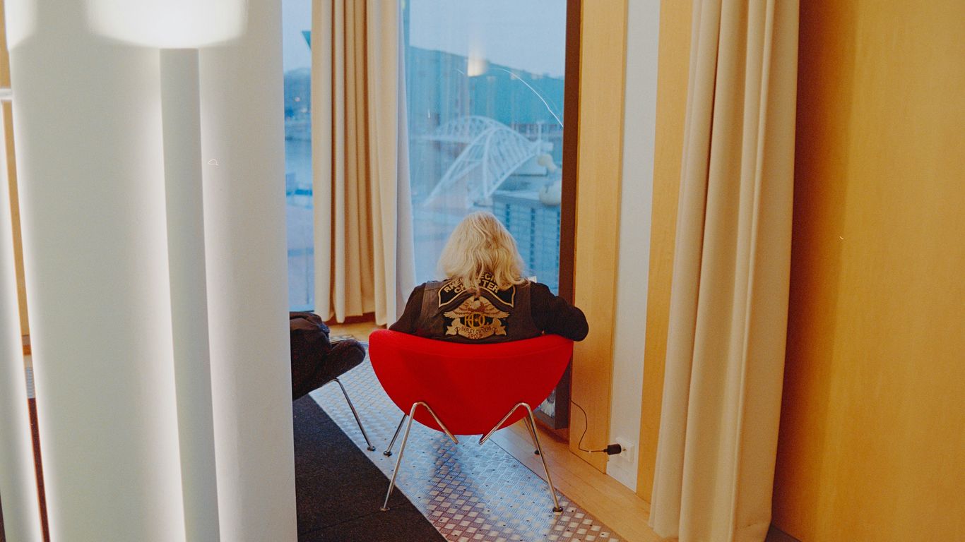 a woman sitting in a red chair looking out a window